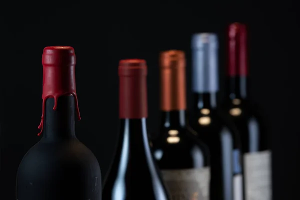 Készlet gallérok vörösbor palackok elszigetelt fekete alapon — Stock Fotó