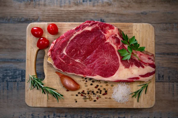 Tahtadaki çiğ T-Bone bifteği ızgaraya hazır. 