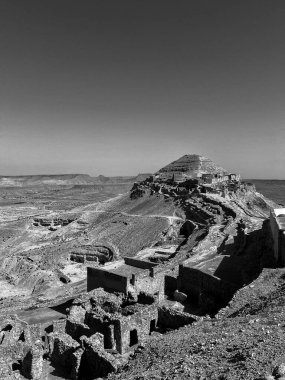 Dolambaçlı yol Tataouine 'deki troglodit köyü Qirmish' e çıkıyor, açık mavi gökyüzü altında toprak tonları ve çöl manzarasıyla karakterize ediliyor, tarihi konutlarını keşfetmeye davet ediyor..