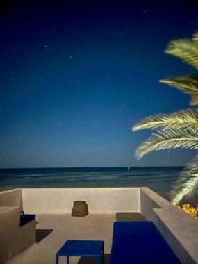 Tunus 'un başkenti Djerba' da, beyaz bir evin çatısında huzur dolu bir ortam yaratmak için yıldızların parlak bir şekilde parladığı sakin bir manzara beliriyor..