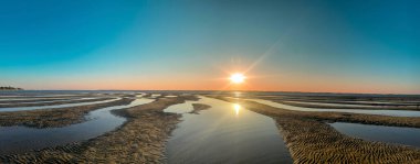 Büyüleyici bir günbatımı Arcachon 'daki Plage Peirere' in sakin güzelliğini yakalar. Altın güneş suyu yansıtıyor ve kumlu sahilde dalgalar çekildikçe sakin bir atmosfer yaratıyor..