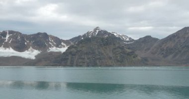 Okyanus su yakınında karla kaplı buzul dağlarının doğal görünümü