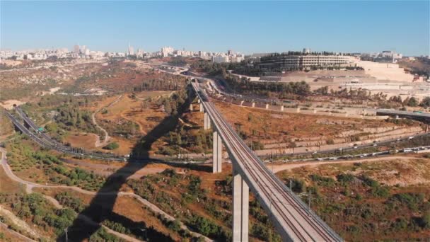 現代の乗客大きな橋で列車 エルサレムの航空機に入るエルサレムの鉄道橋を渡る赤い列車のドローン映像 — ストック動画