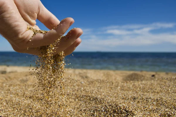 Elini denizin kenarında sahilde kum dökülen