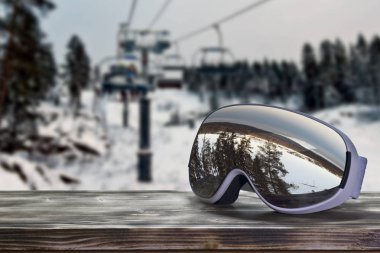 kar maskesi ile ahşap bir masa sandalye Asansör bir Kayak Merkezi, arka planı bir yamaçta ağaçta bir yansımasıdır