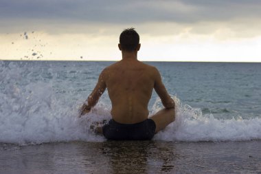 adam lotus poz deniz kıyısı ve dalgalar onu dayak