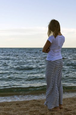 genç güzel ince kız akan ile rüzgar saç ayakta duran mavi deniz kıyısında. kavram beklentileri.