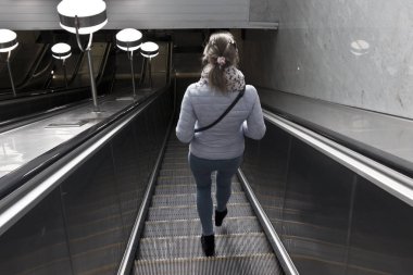 genç kız mavi ceketli bir yürüyen merdiven metro geliyor