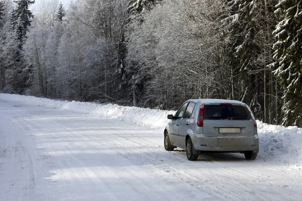 car stopped at the curb on a forest road in winter