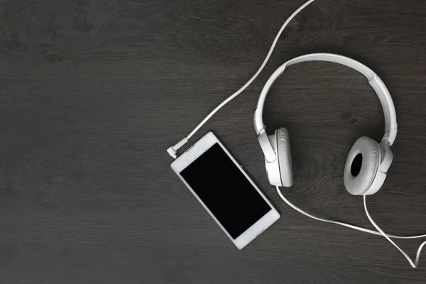 Weiße Kopfhörer Und Ein Weißes Smartphone Auf Einem Holztisch — Stockfoto