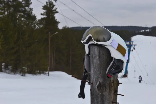 ski helmet with goggles on a wooden pole on the ski slope