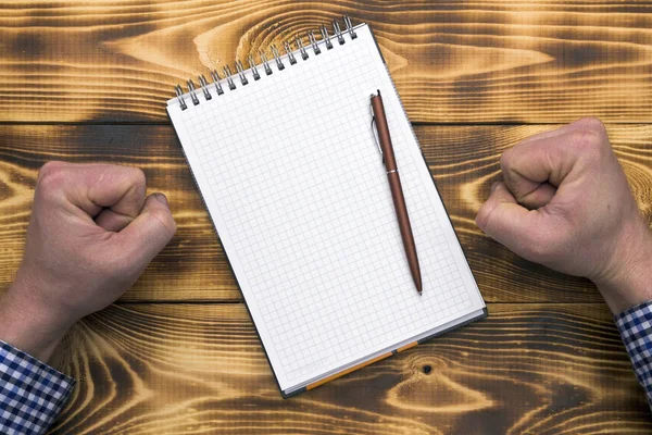 Bir adam sinirlenir ve boş bir defter ve kalem in diği masaya yumruklarını çalar.