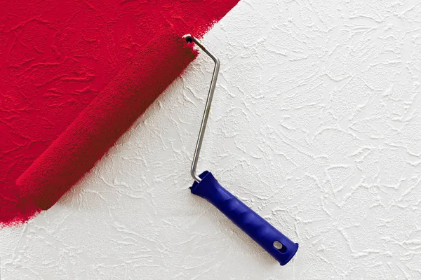 Beyaz duvarda kırmızı fırça darbesi ile boya rulosu