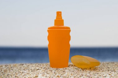 kumlu bir deniz plajında açık bir kapak ile güneş kremi