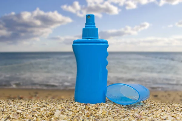 a bottle of sunscreen lotion standing exactly on the sand by the sea