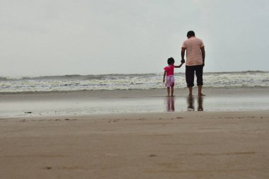 Baba ve kızı birlikte sahilde oynarken. Babası kızını ilk kez deniz tanıtmak. mutlu bir aile.