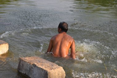 Doğal bir gölde yıkanan bir adam, yaz mevsiminde yaz sıcağında hindistan'ın kırsal kesiminde, Doğa Rezervi'nde kendini serinletiyor..