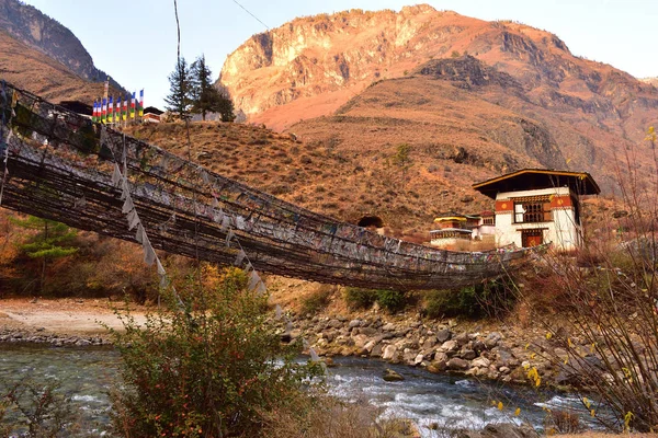Vista lateral del puente colgante a pie con muchas banderas de oración de colores en Bután . — Foto de Stock