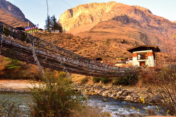 Vista lateral del puente colgante a pie con muchas banderas de oración de colores en Bután . — Foto de Stock