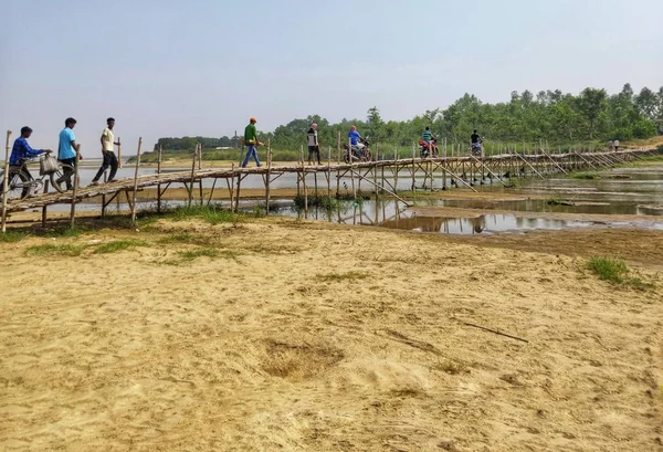 La gente estaba cruzando un río en un puente de bambú hecho a mano . — Foto de Stock