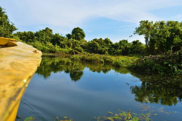 A boat tour in Buxa Tiger Reserve in West Bengal, India. A ride through the jungle. Front of the boat visible to the right. Himalaya mountains in front visible.