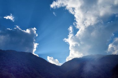 Bulutların arkasından batan güneşin ışınları Bhutan'da kırılır. Kavram - Tanrı'nın nimet