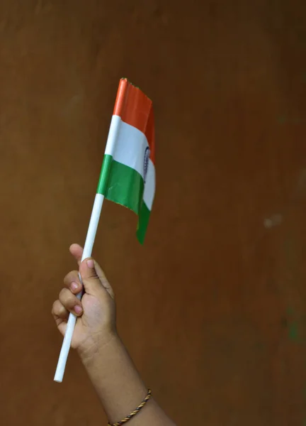 Mão de criança segurando Bandeira Tricolor Nacional Indiana. Isolado sobre fundo de açafrão. Conceito de Dia da Independência da Índia ou Dia da República . — Fotografia de Stock