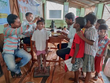 Hindistan kırsalındaki bir ilkokulda bir öğrencinin vücudunu kontrol eden bir doktor..
