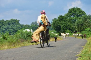 Jhargram, Batı Bengal, Hindistan - Hindistan kırsalında bisiklet süren yaşlı yaşlı Hintli çift. Hint köyünün net bir resmini anlatıyor..