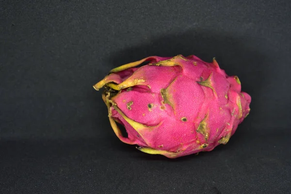 Isolated Exotic dragon fruit (Hylocereus monacanthus, Pitahaya, Pitaya). Bright red violet skinned fruit with violet flesh. Healthy food with black background.