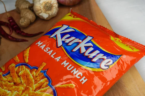 Jhargram, West Bengal, India; August 1, 2025: Black person holding a bag of Kurkure masala munch flavored snacks in a grocery store. Indian tea snacks concepts