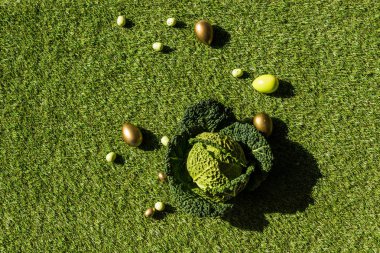 top view of shiny Easter eggs and savoy cabbage on green grass   clipart