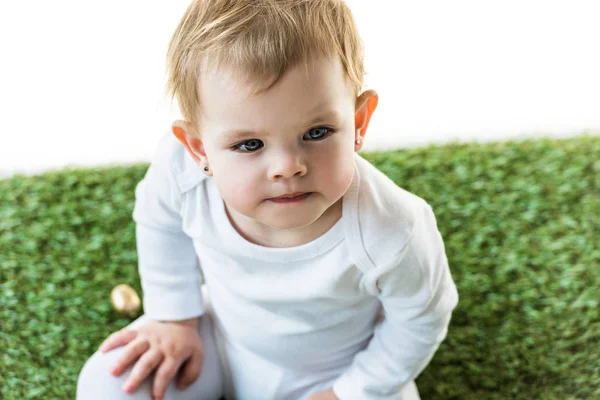 白い上に孤立した緑の草の上に座っている愛らしい物思いの子供 — ストック写真