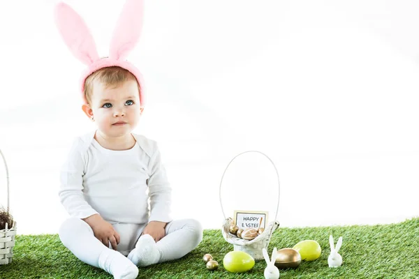 Cute baby sitting near straw basket, Easter eggs and decorative rabbits isolated on white — Stock Image Cute Baby Sitting Straw Basket Easter Eggs Decorative Rabbits Isolated Stock Picture