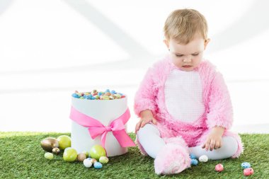 pembe kabarık kostüm sevimli bebek beyaz üzerinde izole renkli Paskalya yumurtaları ile kutu yakın oturan