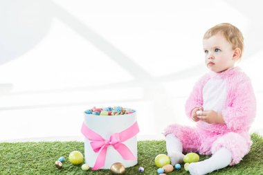 pembe kabarık kostüm sevimli çocuk pembe yay ve renkli Paskalya yumurtaları beyaz üzerinde izole kutusu yakın oturan