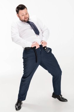 overweight man in formal wear putting on tight pants on white clipart