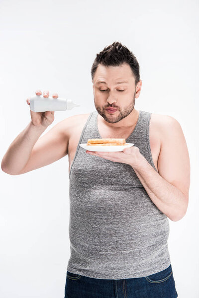 overweight man holding bottle of syrup and waffles isolated on white