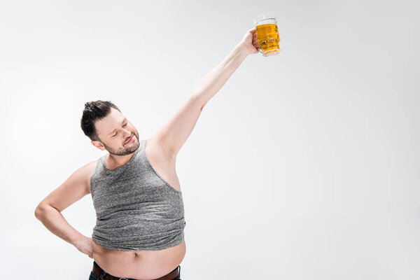 overweight man in tank top holding glass of beer with outstretched hand on white with copy space