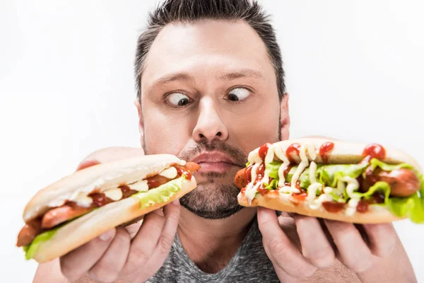 overweight man holding hot dogs and making face expression isolated on white