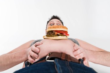 shocked overweight man with burger on belly isolated on white clipart