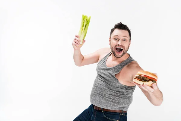 Excité Homme Surpoids Tenant Céleri Hamburger Isolé Sur Blanc Avec — Photo
