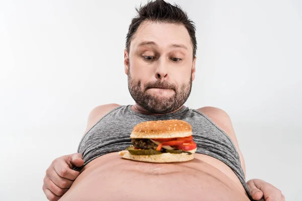 Sovrappeso Uomo Guardando Hamburger Sulla Pancia Isolato Bianco — Foto Stock