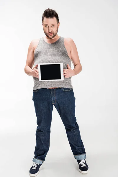太りすぎの男は カメラを見て 白い上に空白の画面でデジタルタブレットを示しています — ストック写真
