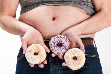 cropped view of overweight man showing belly and holding donuts isolated on white clipart