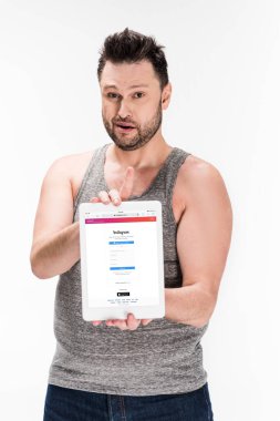 kilolu adam kameraya bakıyor ve beyaz izole ekranda instagram uygulaması ile dijital tablet gösteren