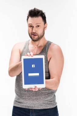 kilolu adam kameraya bakıyor ve beyaz izole ekranda facebook uygulaması ile dijital tablet gösteren