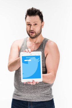 kilolu adam kameraya bakıyor ve beyaz izole ekranda twitter uygulaması ile dijital tablet gösteren