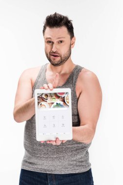 overweight man looking at camera and showing digital tablet with foursquare app on screen isolated on white clipart