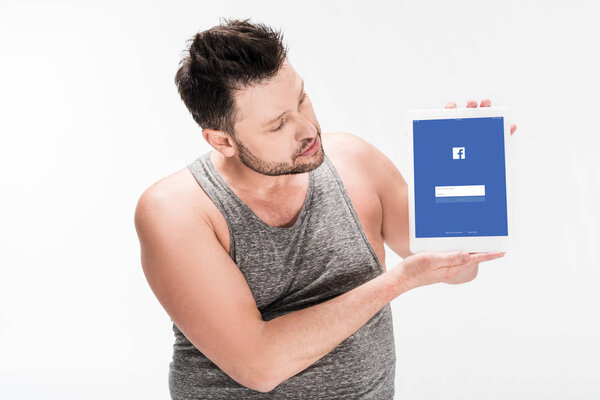 overweight man showing digital tablet with facebook app on screen isolated on white